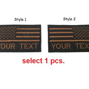Puede incluir: Dos parches bordados en negro y marrón con un diseño de la bandera estadounidense. Cada parche tiene el texto "YOUR TEXT" en la parte inferior. La imagen también incluye el texto "select 1 pcs."