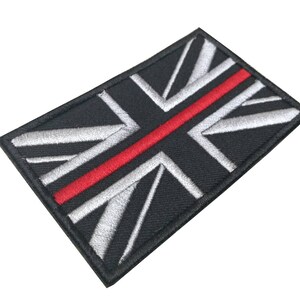 Könnte beinhalten: Schwarzer und weißer gestickter Union-Jack-Flaggen-Patch mit einem dünnen roten Streifen in der Mitte.