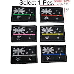 Könnte beinhalten: Sechs gestickte Patches mit schwarzem Hintergrund, einem weißen Kreuz des Südens und einem dünnen, farbigen Streifen in der Mitte. Die Streifen sind grün, rot, rosa, gelb, weiß und blau. Die Patches sind 3,8 cm breit und 2,5 cm hoch. Wählen Sie 1 Stück.