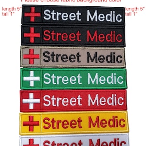 May include: Rectangular embroidered patches with the text "Street Medic" and a red cross symbol. The patches come in various colors, including black, brown, green, red, yellow, and white. Each patch is approximately 5 inches long and 1 inch tall.