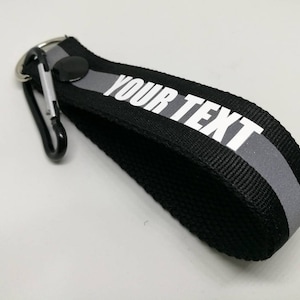 PC 1. Texto personalizado en negro, verde, naranja con pulsera reflectante llavero llavero negro tamaño a presión 12,5 cm x 2,5 cm