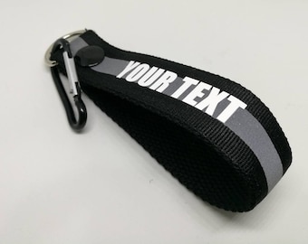 PC 1. Texto personalizado en negro, verde, naranja con pulsera reflectante llavero llavero negro tamaño a presión 12,5 cm x 2,5 cm