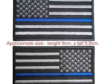 Puede incluir: Dos parches bordados con la bandera estadounidense con una fina línea azul. Los parches son negros con estrellas y rayas blancas y una línea azul en el medio. Los parches miden aproximadamente 9 cm de largo y 5,5 cm de alto.