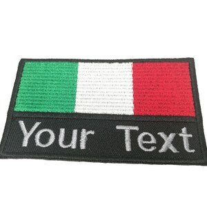 Pode incluir: Um remendo bordado para passar a ferro com a bandeira italiana nas cores verde, branco e vermelho. O remendo tem uma borda preta e uma área retangular preta abaixo da bandeira com o texto "Your Text" em branco.