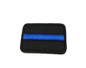 Può includere: Toppa ricamata nera con una sottile striscia blu al centro. La toppa è rettangolare e ha un bordo nero.