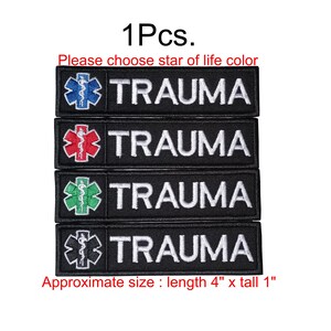 Puede incluir: Parches negros bordados con la palabra "TRAUMA" en blanco. Cada parche presenta un símbolo de la Estrella de la Vida de diferente color: azul, rojo, verde y blanco. Tamaño aproximado: 10 cm de largo x 2,5 cm de alto.