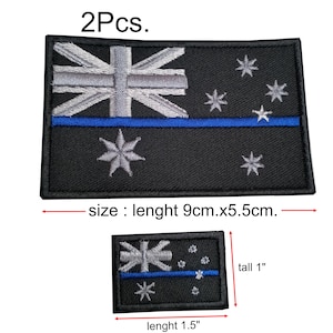 Może przedstawiać: Dwa czarne i szare haftowane naszywki z niebieskim paskiem i flagą Australii. Naszywki mają wymiary 9 cm x 5,5 cm i 1,5 cala x 1 cal.