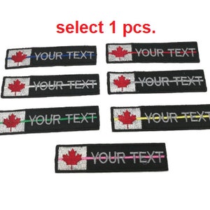 May include: Six black and white embroidered patches with a Canadian flag and the text "YOUR TEXT" in silver. The patches have different colored lines across the flag: blue, red, green, yellow, and pink.