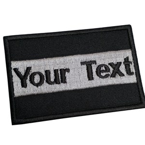 May include: Black and white embroidered patch with the text "Your Text" in black.