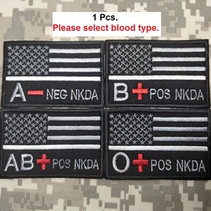 May include: Four black and white embroidered patches with the American flag design. Each patch displays a different blood type: A-, B+, AB+, and O+. The text "NEG NKDA" and "POS NKDA" are also included on each patch. The text "1 Pcs. Please select blood type." is at the top.