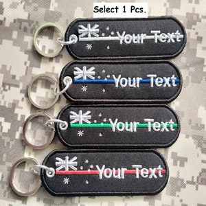 May include: Four black keychains with a white star and the text "Your Text" on each. The keychains have different colored stripes: white, blue, green, and red.