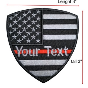 Puede incluir: Parche bordado en blanco y negro con forma de escudo con una línea roja en el medio. El parche presenta una bandera estadounidense estilizada con el texto "Your Text" en letras blancas. El parche mide 7,6 cm de alto y 7,6 cm de ancho.