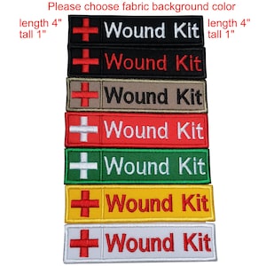 以下が含まれることがあります： 赤十字のシンボルが付いた「Wound Kit」と書かれた刺繍パッチのスタック。パッチは黒、赤、ベージュ、緑、黄色、白など様々な色があります。各パッチのサイズは約10cmの長さと2.5cmの高さです。
