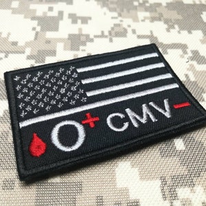 May include: Black embroidered patch with a white American flag, a red blood drop, and the text "O+ CMV-".