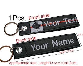 May include: A black key chain with a red and white Canadian flag and the text "Your Text" on the front side. The back side has the text "Your Name". The key chain measures approximately 13.5 inches long and 3 inches tall.