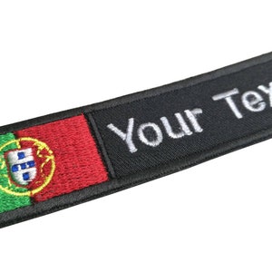 Peut inclure: Écusson brodé noir avec le drapeau portugais sur le côté gauche et le texte "Your Text" sur le côté droit.