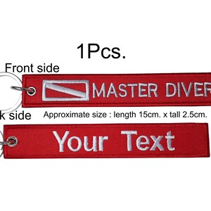 May include: Red rectangular keychain with silver ring. The front side reads "MASTER DIVER" with a white and red scuba diving logo. The back side says "Your Text". Approximate size: 15cm long x 2.5cm tall.