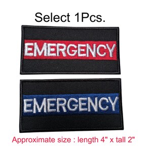 Op de afbeelding: Twee zwarte geborduurde patches met het woord "EMERGENCY" in witte letters. De bovenste patch heeft een rode streep en de onderste patch heeft een blauwe streep. De patches zijn ongeveer 10 cm lang en 5 cm hoog.
