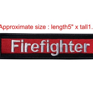 May include: A rectangular patch with the word "Firefighter" embroidered in white on a red background. The patch is bordered by a black frame. Approximate size: 12.7 cm long x 3.2 cm tall.