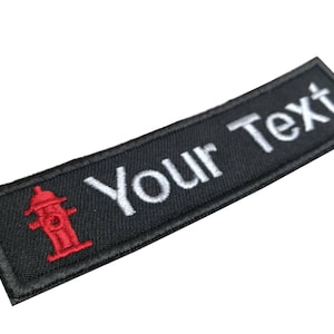 May include: Black embroidered patch with a red fire hydrant and the text "Your Text" in white.