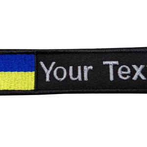 May include: Black embroidered patch with the Ukrainian flag and the text "Your Text" in white.