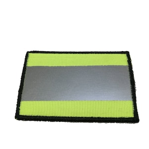 Puede incluir: Un parche reflectante amarillo y plateado con borde negro.