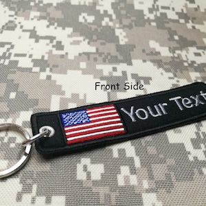 May include: Black keychain with a small American flag and the text "Your Text" embroidered on it.