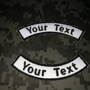 Peut inclure: Deux patchs brodés blancs avec une bordure noire. Les patchs sont en forme d'arc et portent le texte "Your Text".