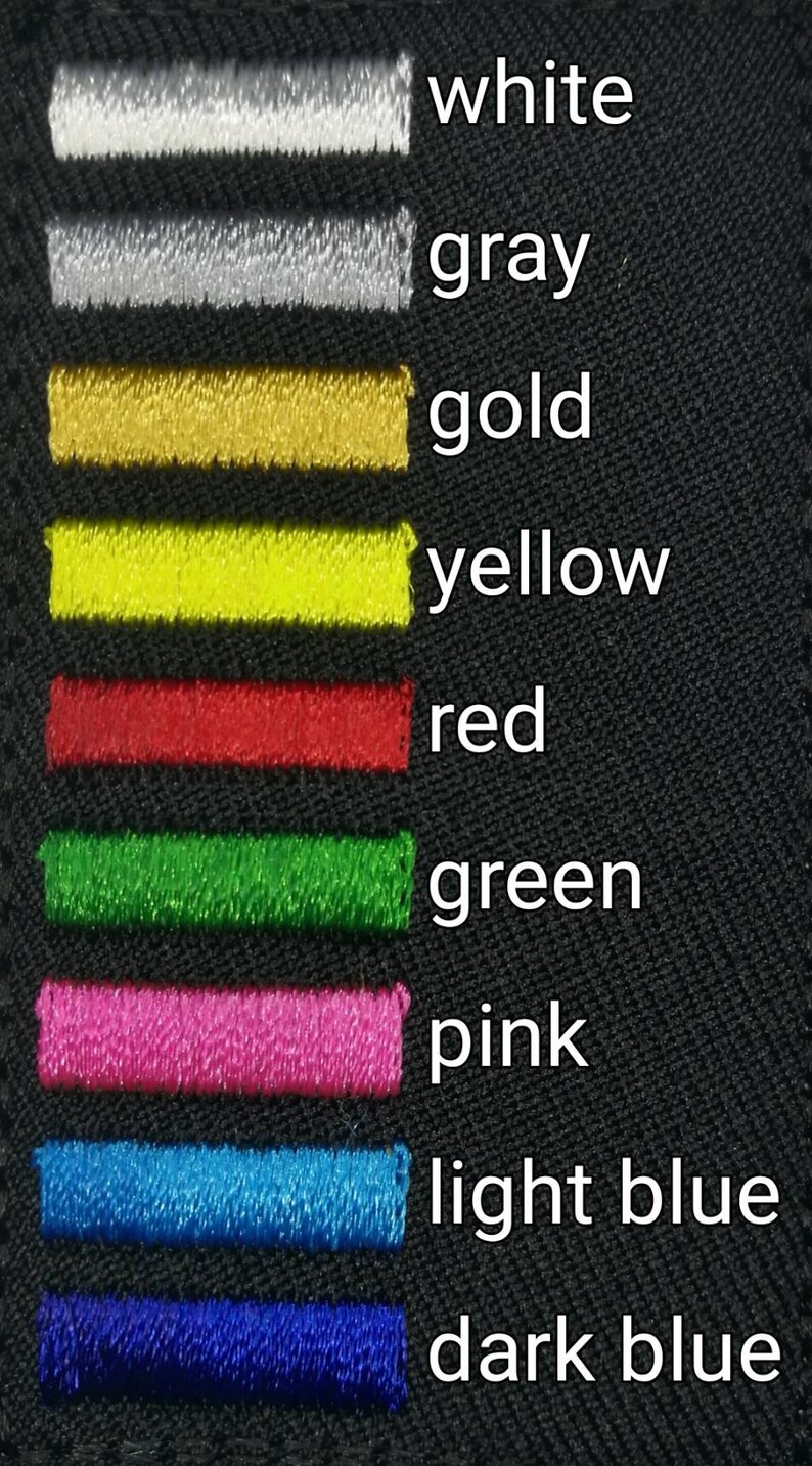 May include: A black fabric swatch with rows of colored thread samples. The colors are white, gray, gold, yellow, red, green, pink, light blue, and dark blue.