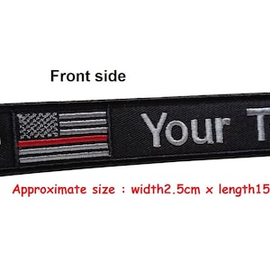 May include: Black keychain with a red, white, and blue American flag with a red stripe across the middle. The keychain has a silver ring and the text "Your Text" in silver lettering.