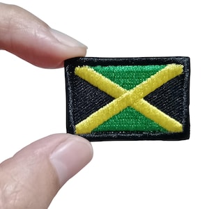 Peut inclure: Un écusson rectangulaire brodé représentant le drapeau de la Jamaïque. Le motif se compose d'une croix de saint André jaune divisant l'écusson en quatre triangles, avec deux triangles verts en haut et en bas et deux triangles noirs sur les côtés.