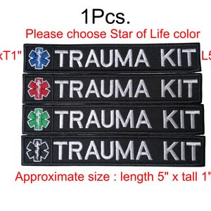 Puede incluir: Parches negros bordados con el texto "TRAUMA KIT" en blanco. Cada parche presenta un símbolo de la Estrella de la Vida de diferente color: azul, rojo, verde y blanco. Tamaño aproximado: 12,7 cm de largo x 2,5 cm de alto.