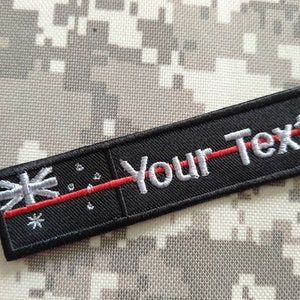 Könnte beinhalten: Schwarzer gestickter Patch mit einer roten Linie und weißem Text, der "Your Text" lautet. Der Patch zeigt eine stilisierte Flagge mit einem weißen Kreuz und Sternen.