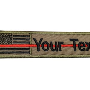 May include: An embroidered patch in green with a red line and an American flag on the left side and the text "Your Text" on the right side.
