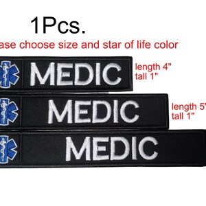 Könnte beinhalten: Schwarze, gestickte Aufnäher mit dem weißen Wort „MEDIC“. Jeder Aufnäher hat ein blaues Star of Life-Emblem. Größen: 10 cm, 13 cm und 15 cm lang, alle 2,5 cm hoch. Der Text „Bitte wählen Sie Größe und Farbe des Lebenssterns“ ist ebenfalls sichtbar.