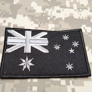 May include: Black embroidered patch featuring the Australian flag. The flag displays a white Union Jack in the top left corner and a constellation of seven white stars on a black background.