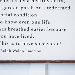 May include: A framed wooden sign with a white background and black text. The text is a quote by Ralph Waldo Emerson, with the words "This is to have succeeded!" prominently displayed.