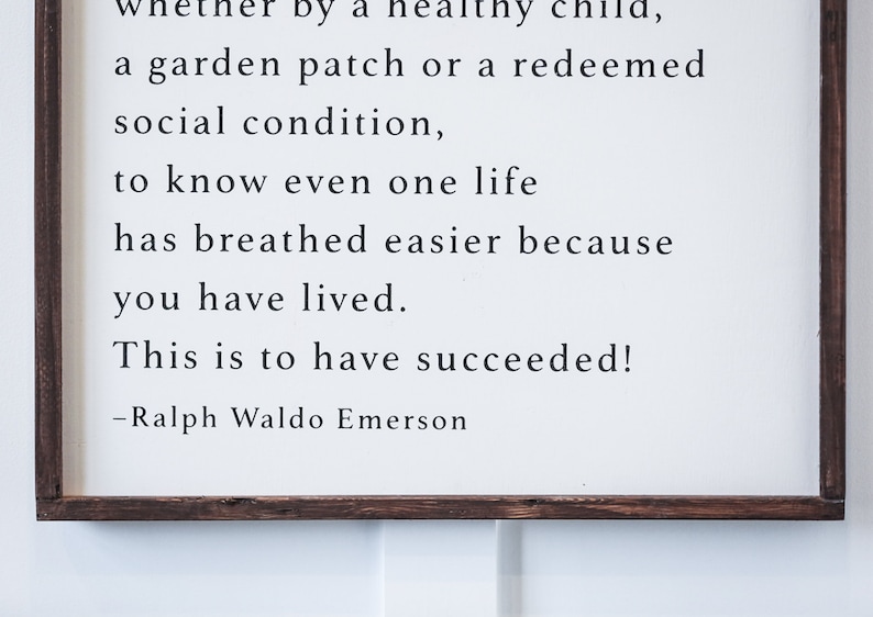 May include: A framed wooden sign with a white background and black text. The text is a quote by Ralph Waldo Emerson, with the words "This is to have succeeded!" prominently displayed.