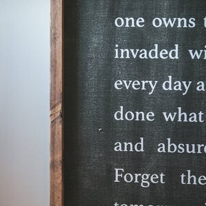 May include: Black chalkboard sign with white text that reads "that every c He is rich one owns t invaded wi every day a done what and absur Forget the tomorrow i and serenel"