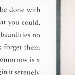 May include: A black and white framed print with a quote that reads: "y and be done with ne what you could. and absurdities no ept in; forget them can. Tomorrow is a all begin it serenely"