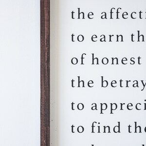 May include: A white wooden sign with black text. The text includes phrases like "to win the intelligent" and "to earn the of honest." The sign has a dark brown wooden frame.