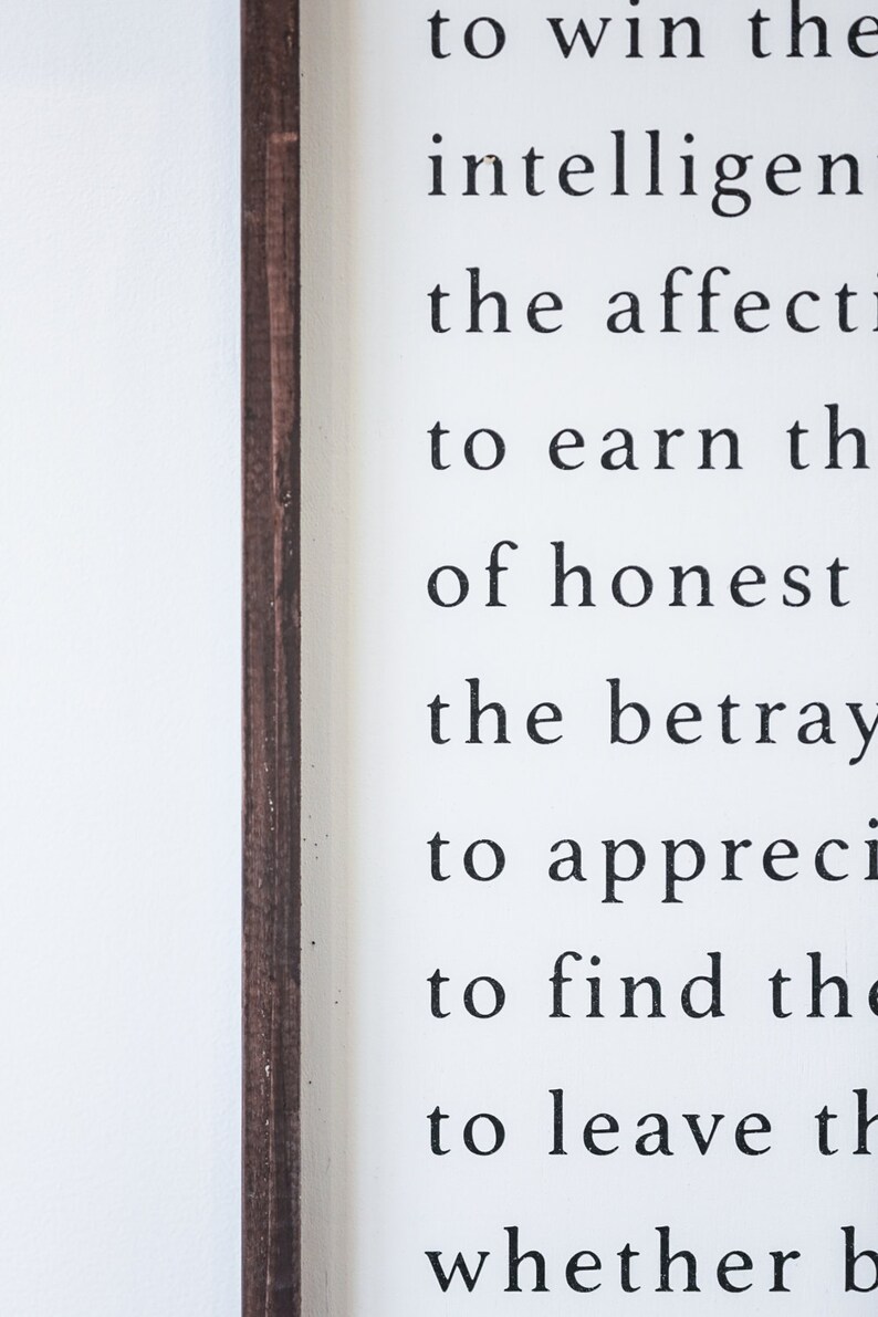 May include: A white wooden sign with black text. The text includes phrases like "to win the intelligent" and "to earn the of honest." The sign has a dark brown wooden frame.