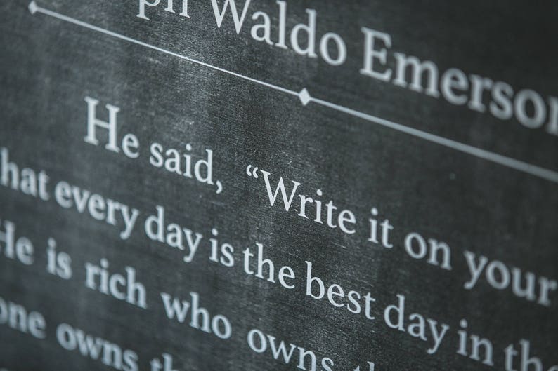 May include: Black chalkboard with white text that reads "Ralph Waldo Emerson" and "He said, "Write it on your hat every day is the best day in the".