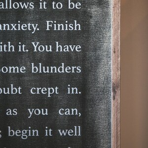 May include: Black wooden sign with white text that reads: "e day, and no allows it to be anxiety. Finish ith it. You have ome blunders oubt crept in. as you can, begin it well gh a spirit to be old nonsense."