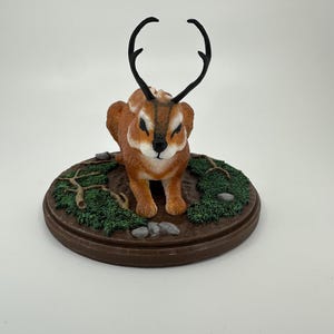 Full color Jackalope statue in “catloaf” pose with antelope style color scheme and modified antlers