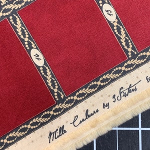 Puede incluir: Tela roja con un patr&oacute;n geom&eacute;trico en blanco y negro. La tela tiene un borde blanco con el texto "Mills Cabanus by 5 Sisters" escrito en negro.