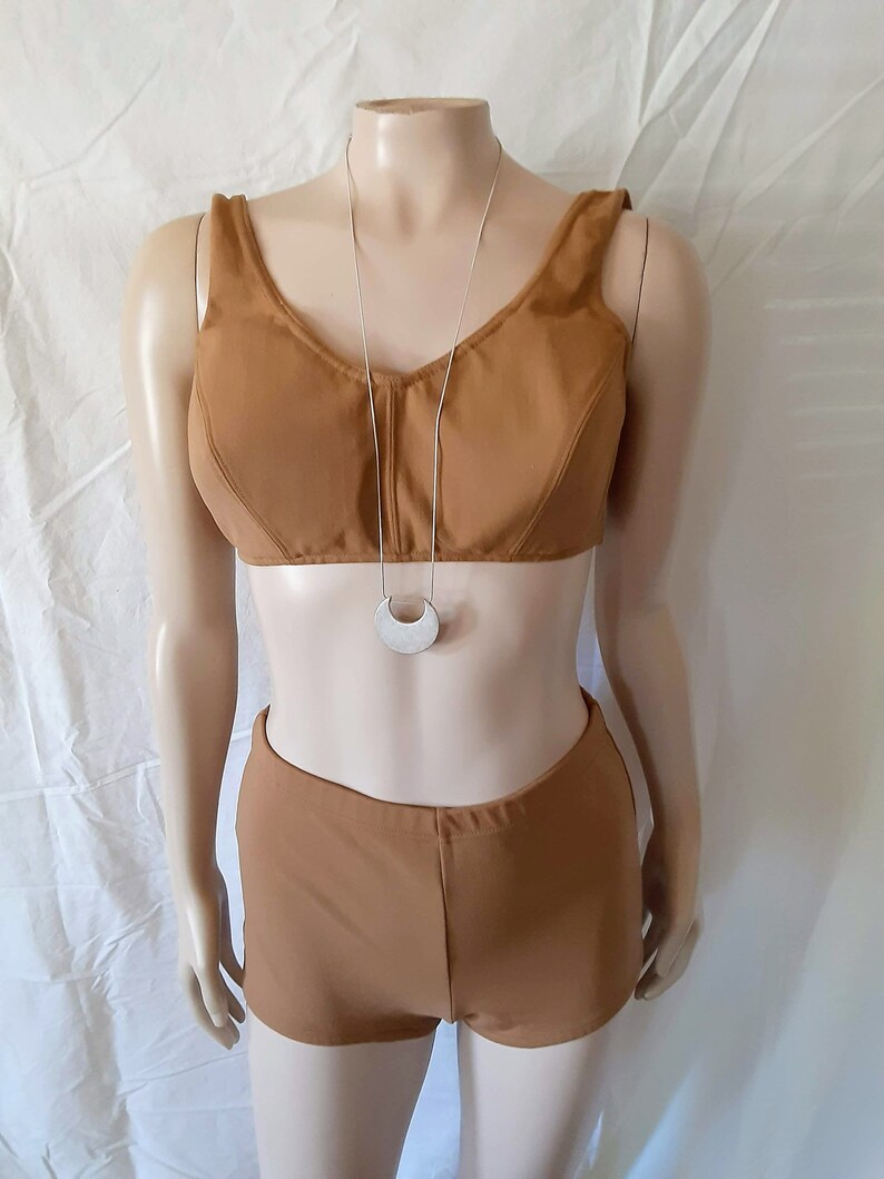 May include: A brown two-piece swimsuit with a halter top and high-waisted shorts. The swimsuit is on a white mannequin.