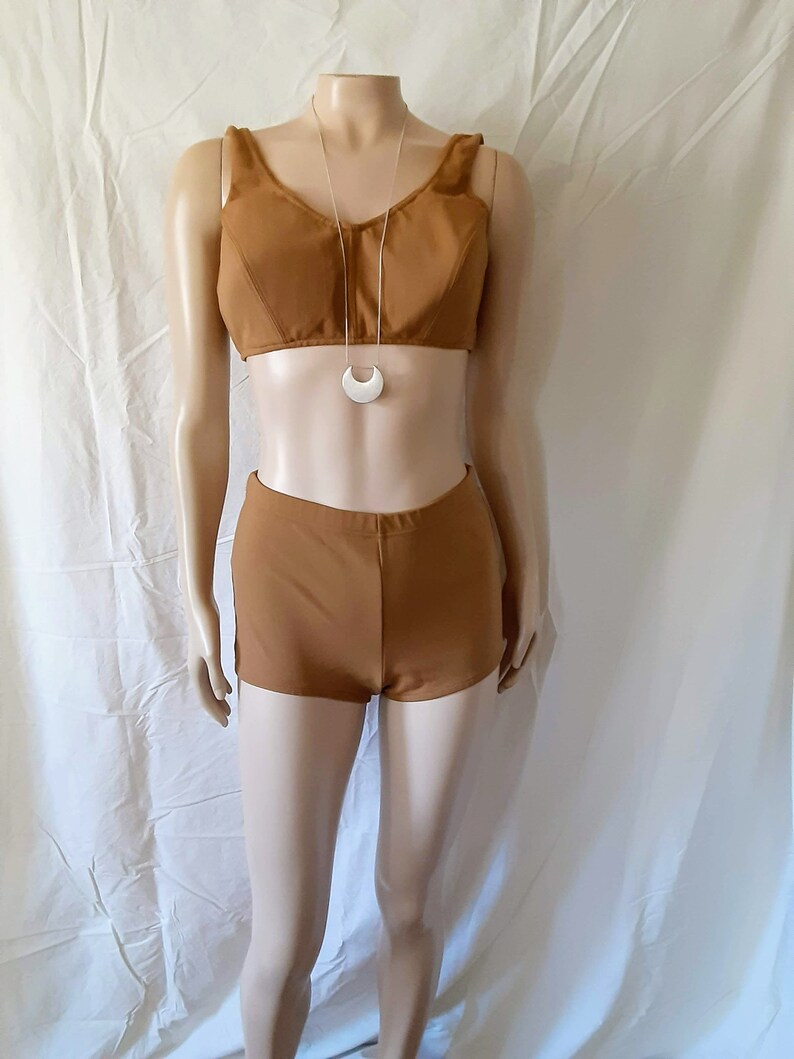 May include: A brown swimsuit with a halter top and high-waisted shorts. The swimsuit is on a mannequin and has a silver crescent moon necklace.