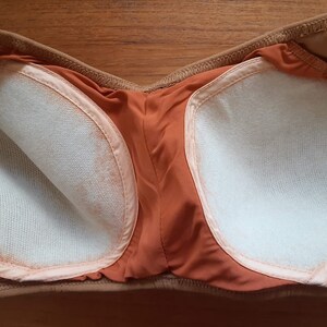 May include: The inside of a strapless bra with brown fabric and white padding.