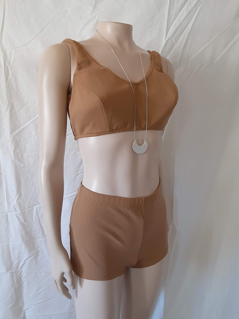 May include: A brown two-piece swimsuit with a halter top and high-waisted shorts. The top has a scoop neckline and the shorts have a wide waistband. The swimsuit is on a white mannequin.